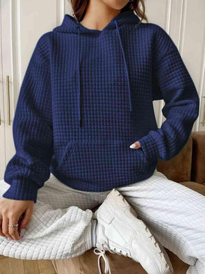 a woman sitting on a couch wearing a blue sweater and white pants