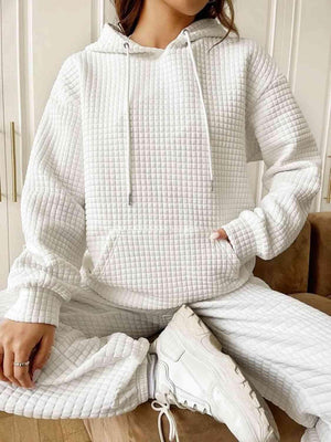 a woman sitting on a couch wearing a white sweater and pants