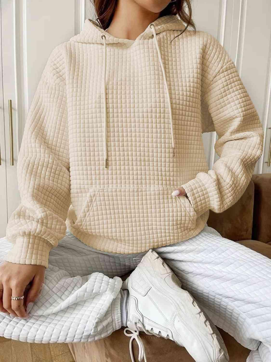 a woman sitting on a couch wearing a beige sweater and white pants