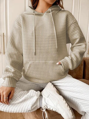 a woman sitting on a couch wearing a hoodie