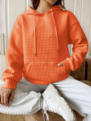 a woman sitting on a couch wearing an orange hoodie