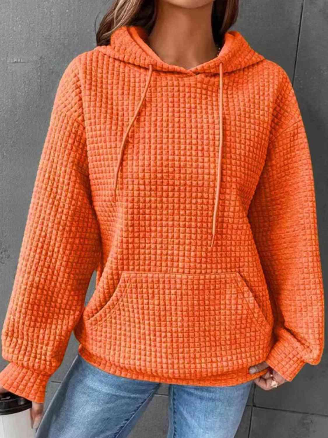 a woman wearing an orange sweater and jeans