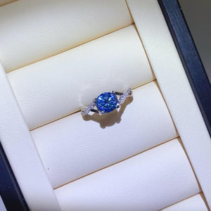 a blue diamond ring sitting on top of a white box