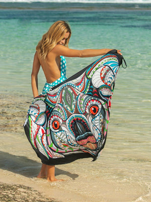 a woman standing on a beach holding a large piece of cloth