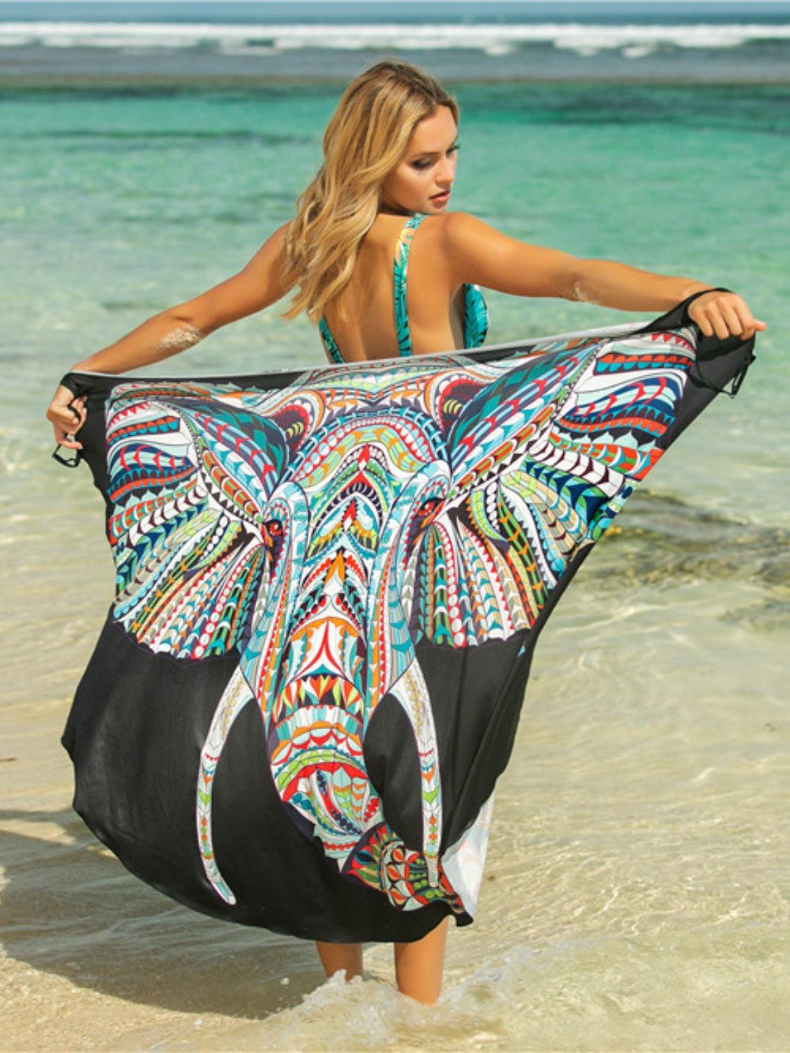 a woman in a bathing suit holding an elephant print cover up