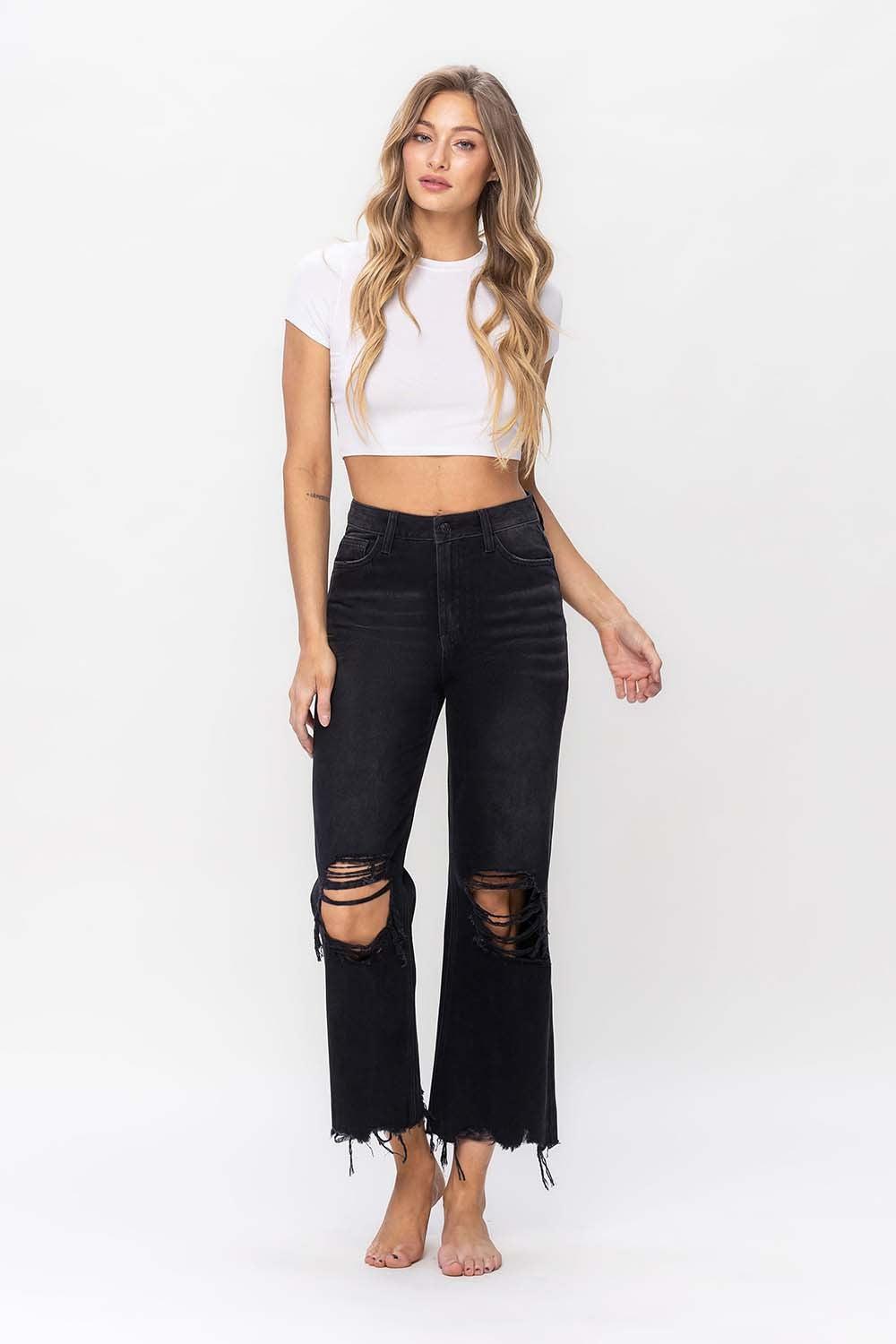 a woman wearing black ripped jeans and a white crop top