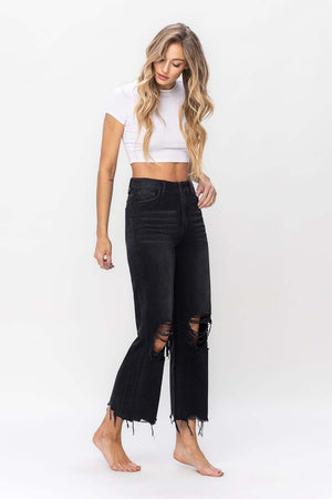 a woman wearing black ripped jeans and a white crop top