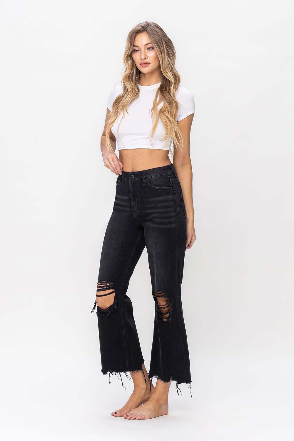 a woman wearing a white crop top and black ripped jeans