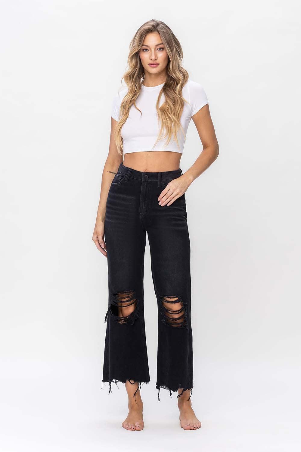 a woman wearing a white crop top and black ripped jeans