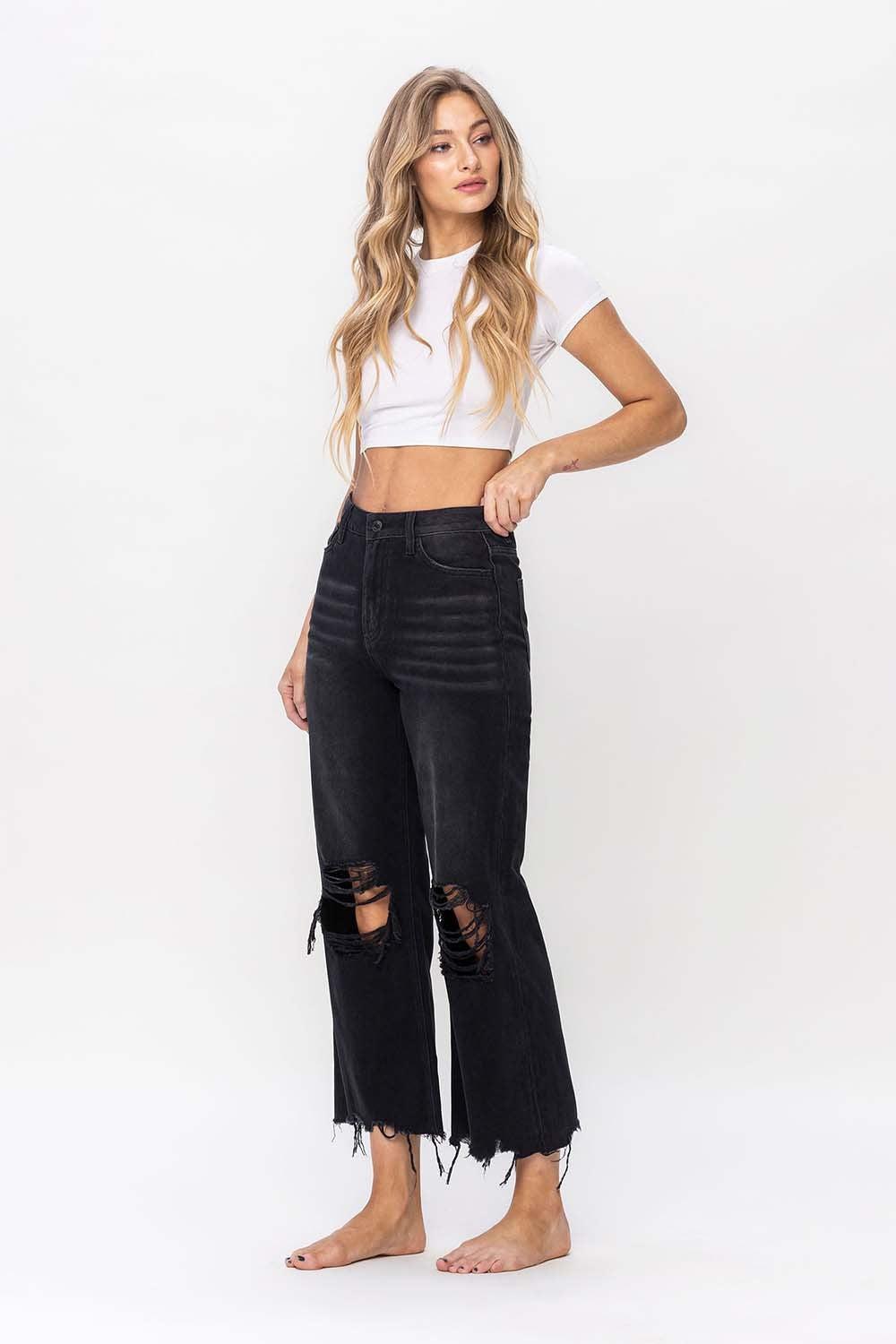 a woman wearing a white crop top and black ripped jeans