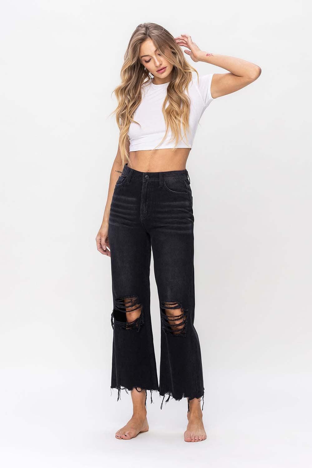 a woman wearing a white crop top and black ripped jeans