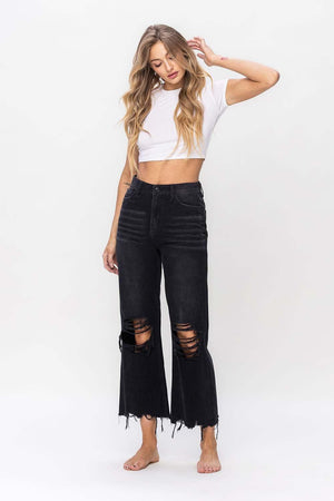 a woman wearing a white crop top and black ripped jeans