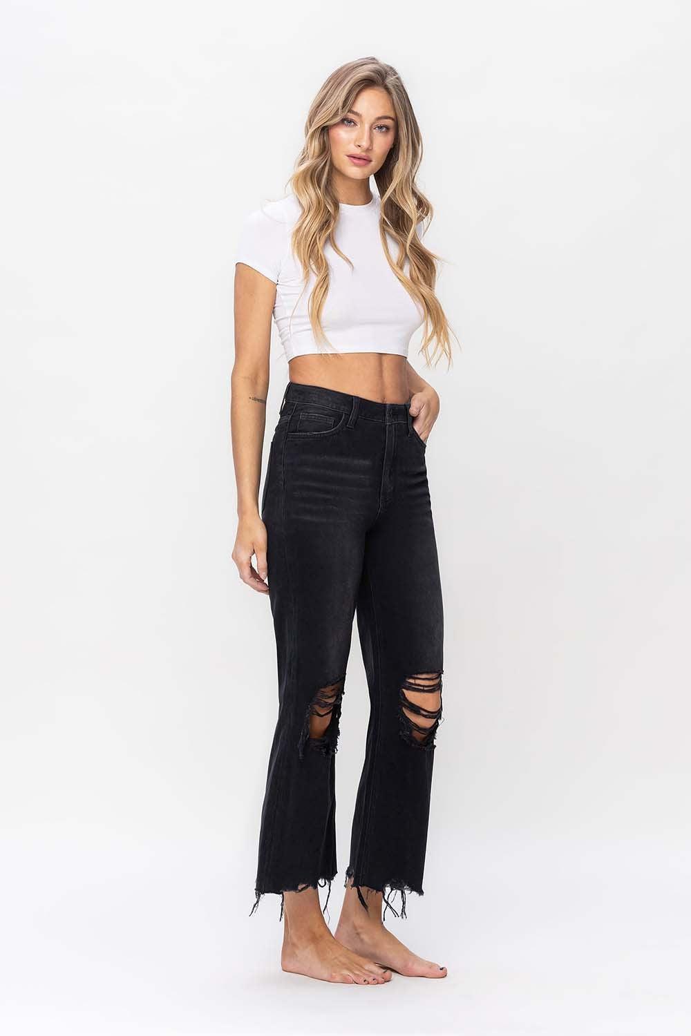 a woman wearing a white crop top and black ripped jeans