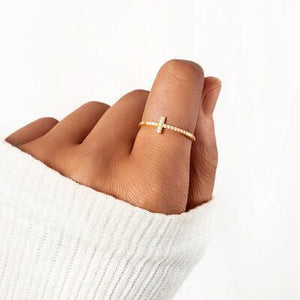 a woman's hand with a cross ring on it