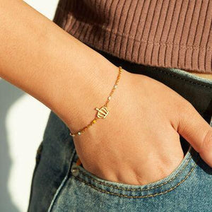 a woman wearing a gold bracelet with a letter on it