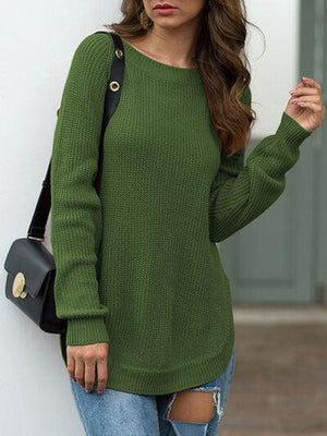 a woman leaning against a wall wearing a green sweater