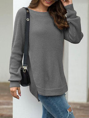 a woman wearing a gray sweater and ripped jeans