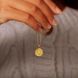 a woman holding a yellow necklace with a flower on it