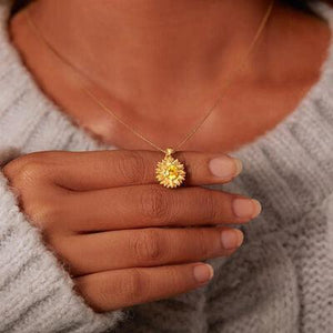 a woman wearing a yellow necklace and a white sweater