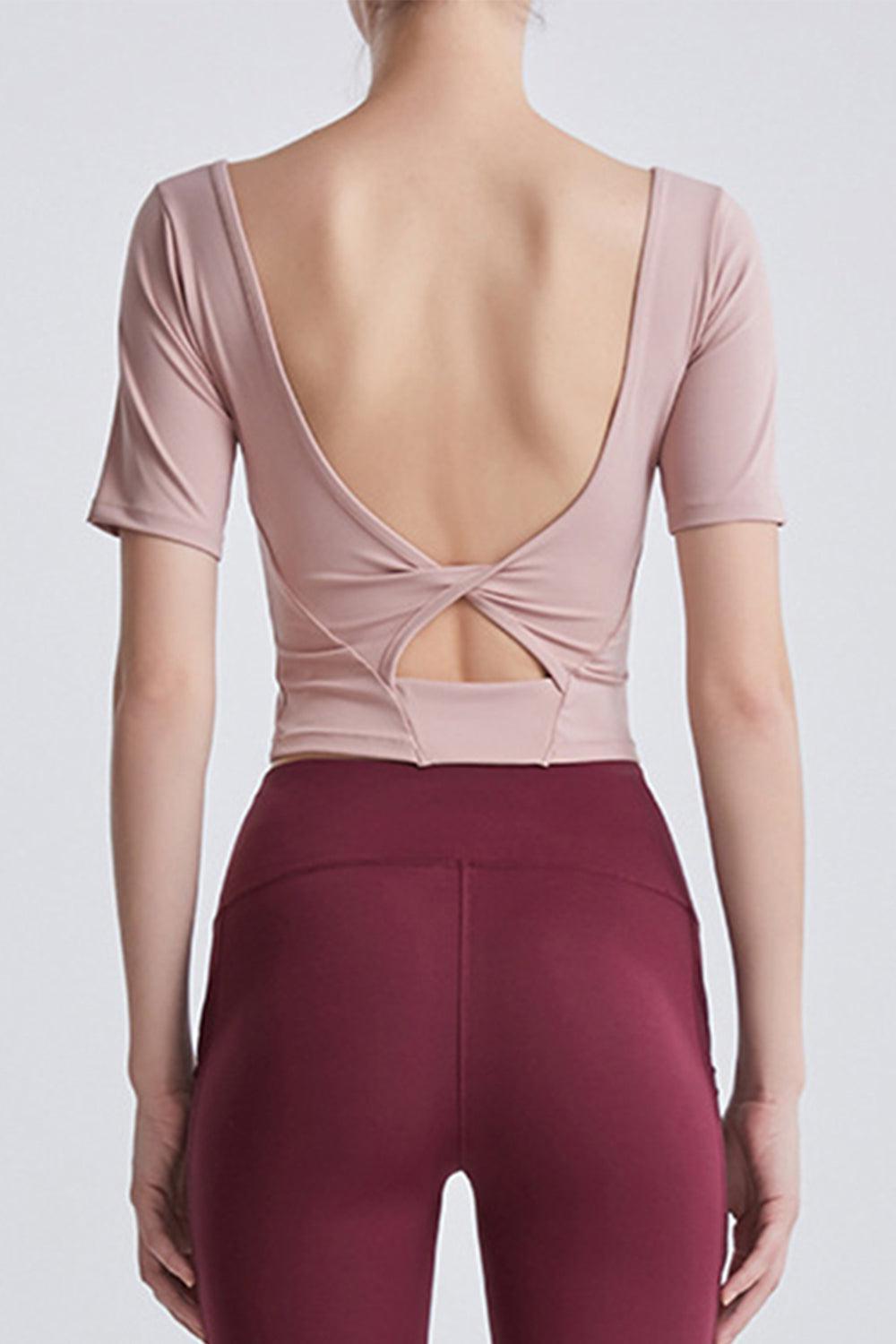 the back of a woman wearing a pink top and maroon leggings