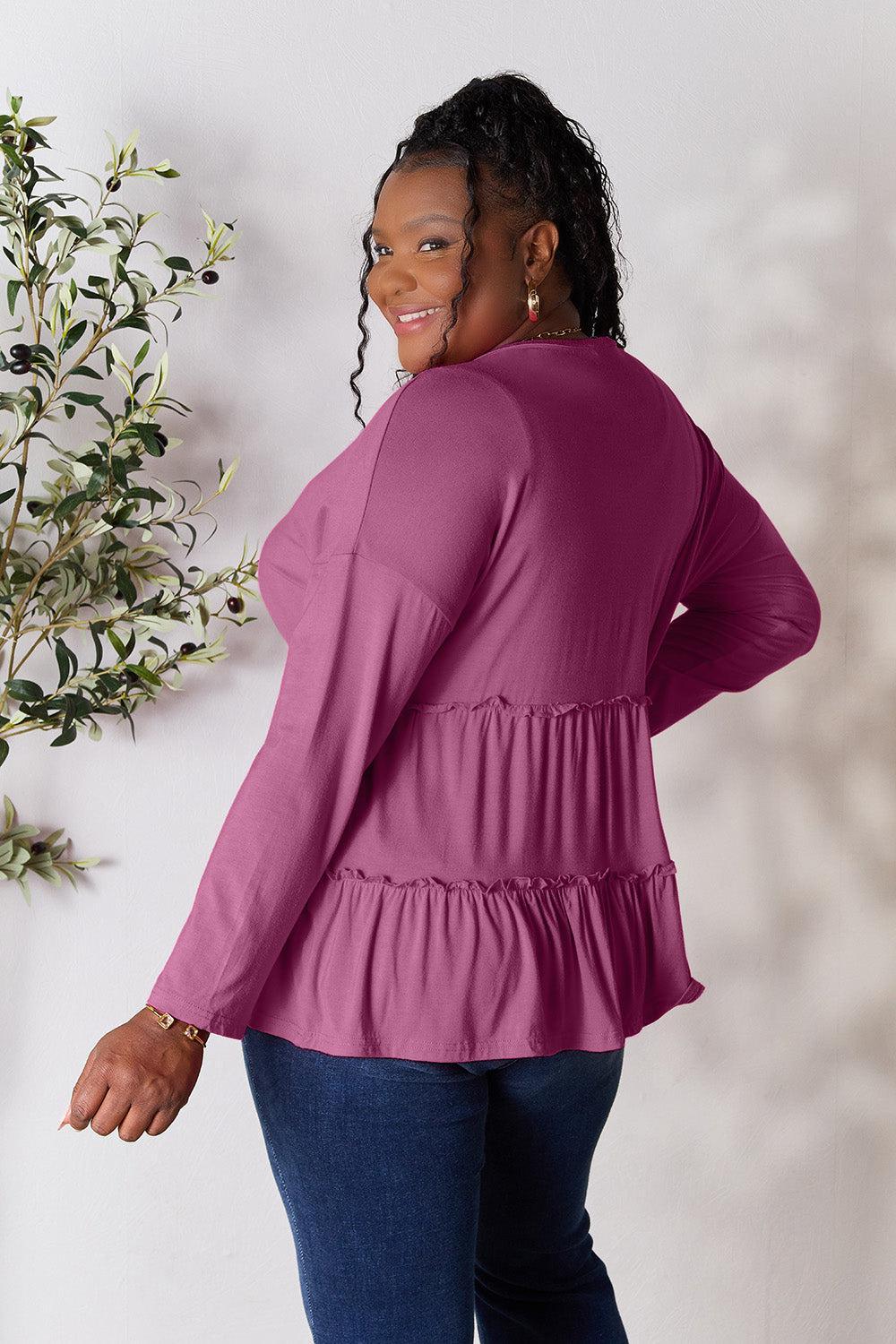 a woman standing next to a plant wearing a pink top