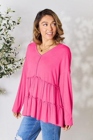 a woman standing in front of a plant wearing a pink top