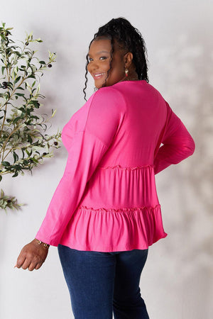 a woman in a pink top standing next to a plant