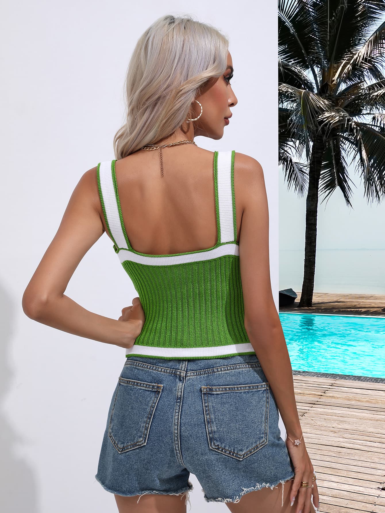 a woman standing next to a pool wearing a green tank top