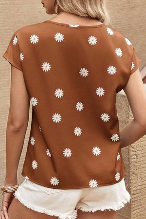 a woman wearing a brown top with white flowers on it