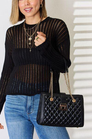 a woman in a black sweater holding a black purse