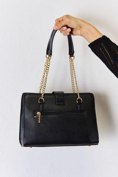 a person holding a black purse with a gold chain