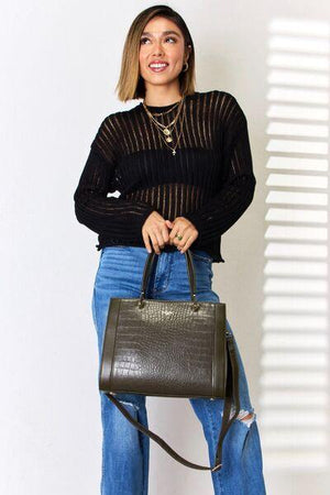a woman is holding a black purse and posing for a picture