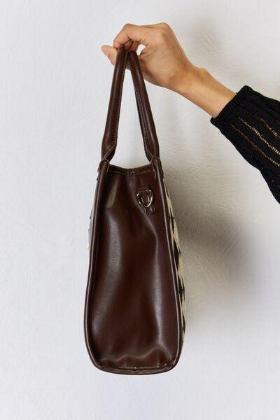a hand holding a brown purse on a white wall
