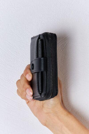 a hand holding a black case with a zipper