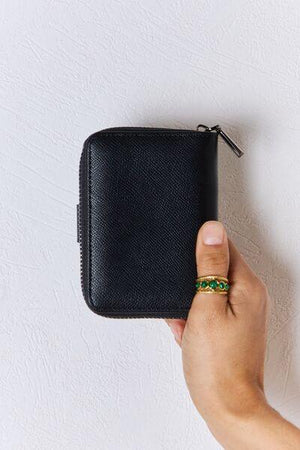 a person holding a black wallet with a green ring on it
