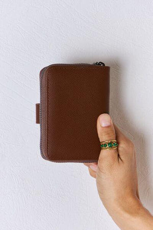 a hand holding a wallet with a ring on it