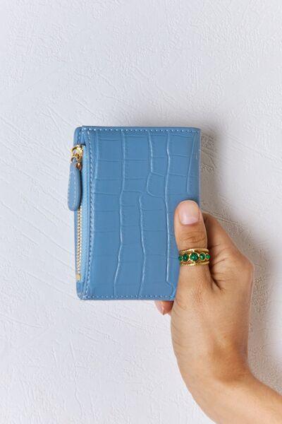 a hand holding a blue wallet with a gold ring