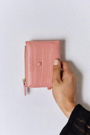 a person holding a pink wallet in their hand