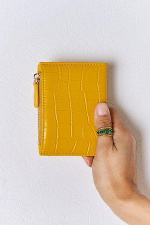 a person is holding a yellow wallet in their hand