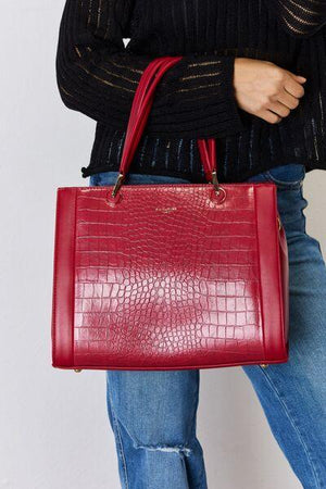 a woman is holding a red handbag