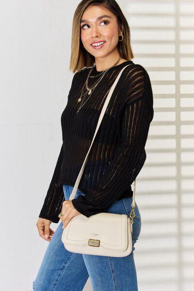 a woman in a black sweater and jeans holding a white purse