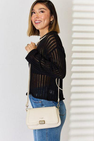 a woman in a black sweater and jeans holding a white purse