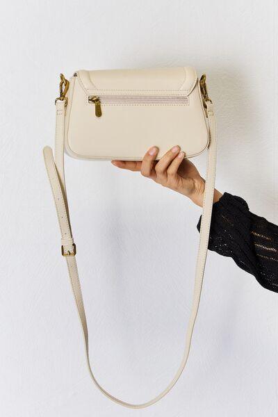 a hand holding a white purse over a white wall