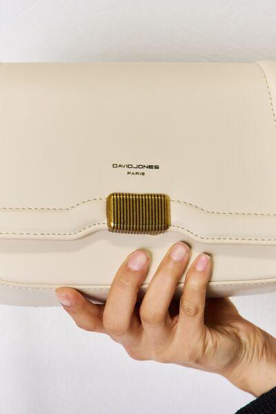 a woman holding a white purse with a gold metal buckle