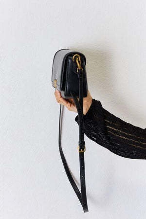 a woman holding a black purse with a gold handle