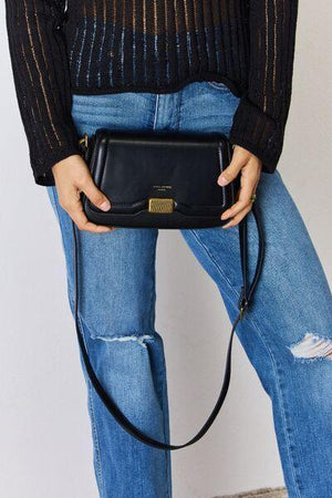 a woman in ripped jeans holding a black purse