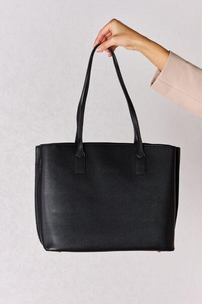 a woman holding a black leather tote bag
