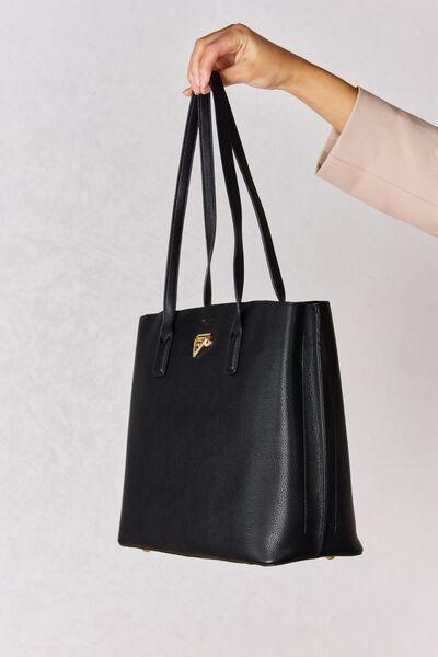 a hand holding a black purse with a gold logo