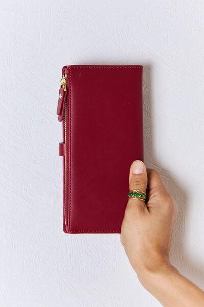 a hand holding a red leather wallet