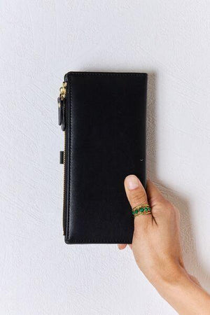 a hand is holding a black leather case